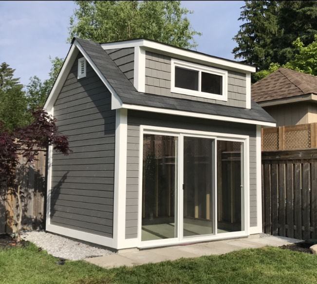 Canexel Copper Creek shed design 9' x 12' in a backyard featuring 9' sliding patio doors with large horizontal sliding window as seen from the front. Id number 5777.