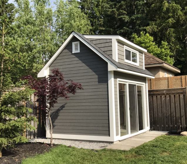 Canexel Copper Creek shed design 9' x 12' in a backyard featuring large horizontal sliding window and a wooden vent as seen from the side. Id number 5777.