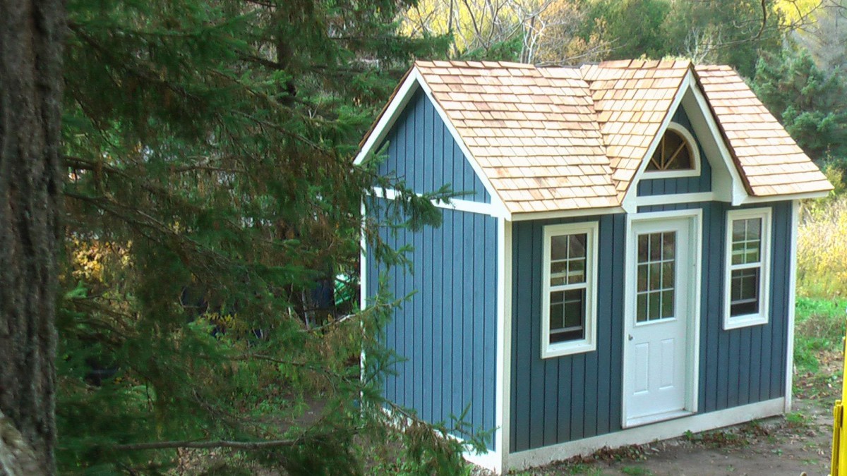 Cedar Copper creek shed design 8' x 12' in a backyard featuring metal deluxe lite single door and single hung vinyl windows as seen from the side. ID number 5768.