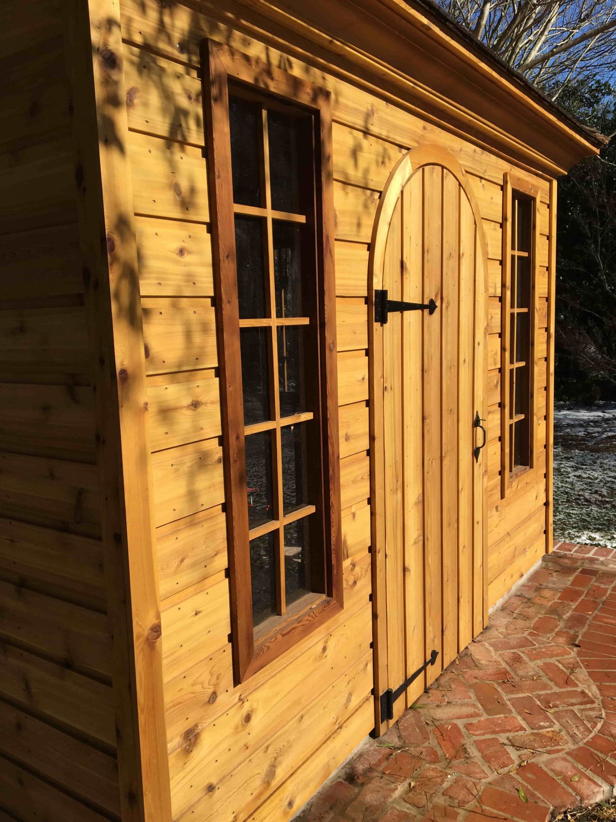 Backyard Melbourne shed plan 10' x 10' featured with rough cedar arched door and casement window as seen from the side. Id number 5744.
