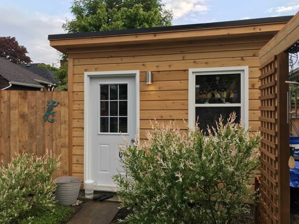Cedar urban studio home studio design 7' x 12' featured with white metal vinyl doors and a sliding window as seen from the front. Id number 5738.