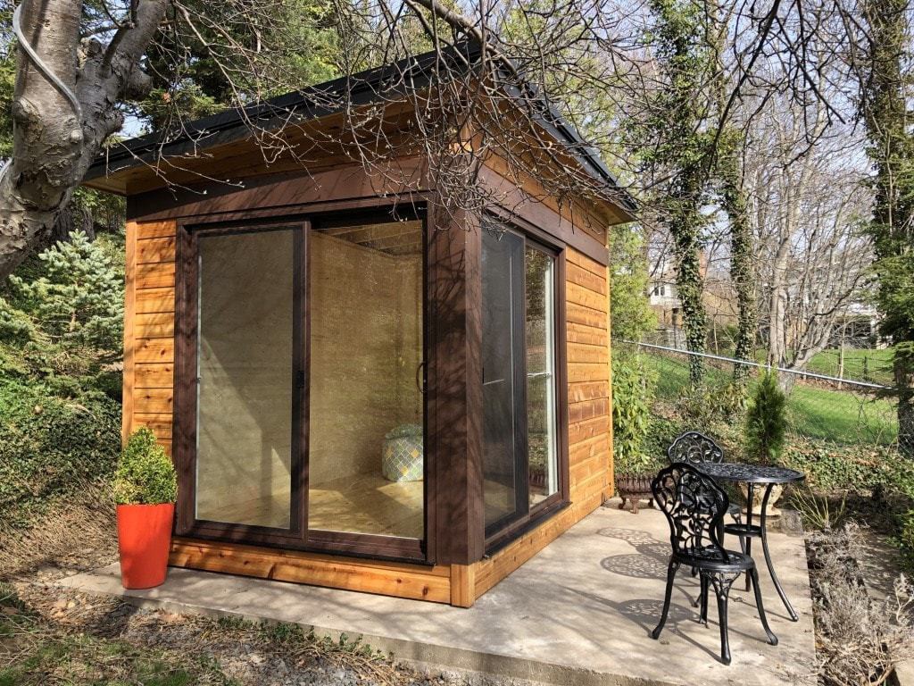 Planed cedar home studio design 8' x 12' in a  backyard with 2 sets of metal vinyl and glass sliding doors in the front and side. ID number 5726.