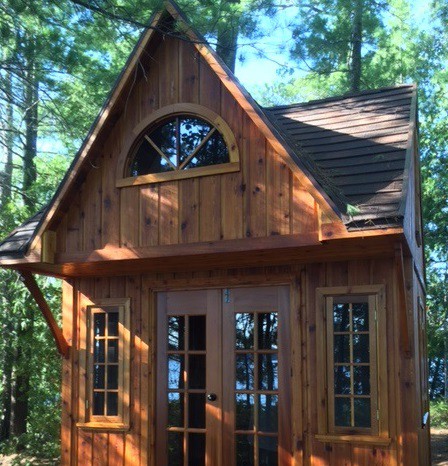 Bala Bunkie cabin design with a fan arch window and a shed dormer in woods seen from the front1. ID number