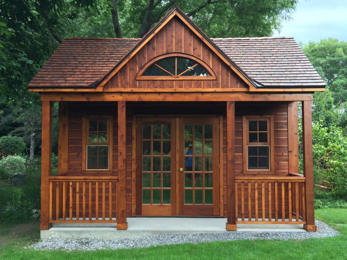 Canmore cabin design 14x16  with large clear sliding windows and french doors in a yard seen front the front. ID number