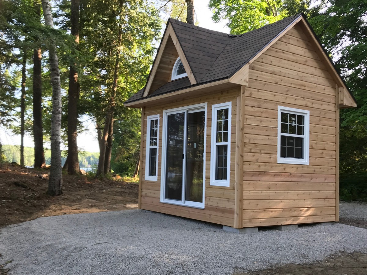 Cedar Copper Creek 9' x 12' sits on the lakeside featured with metal vinyl windows and a sliding door side profile closeup. Id number 5728-3.