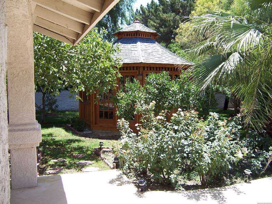 San cristobal gazebo design 16' in garden with stained finish seen from left.ID number 3426-1.