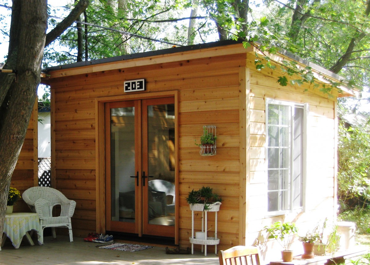 Urban Studio shed plan 10x12 in a garden with cedar channel and single french door. ID number-