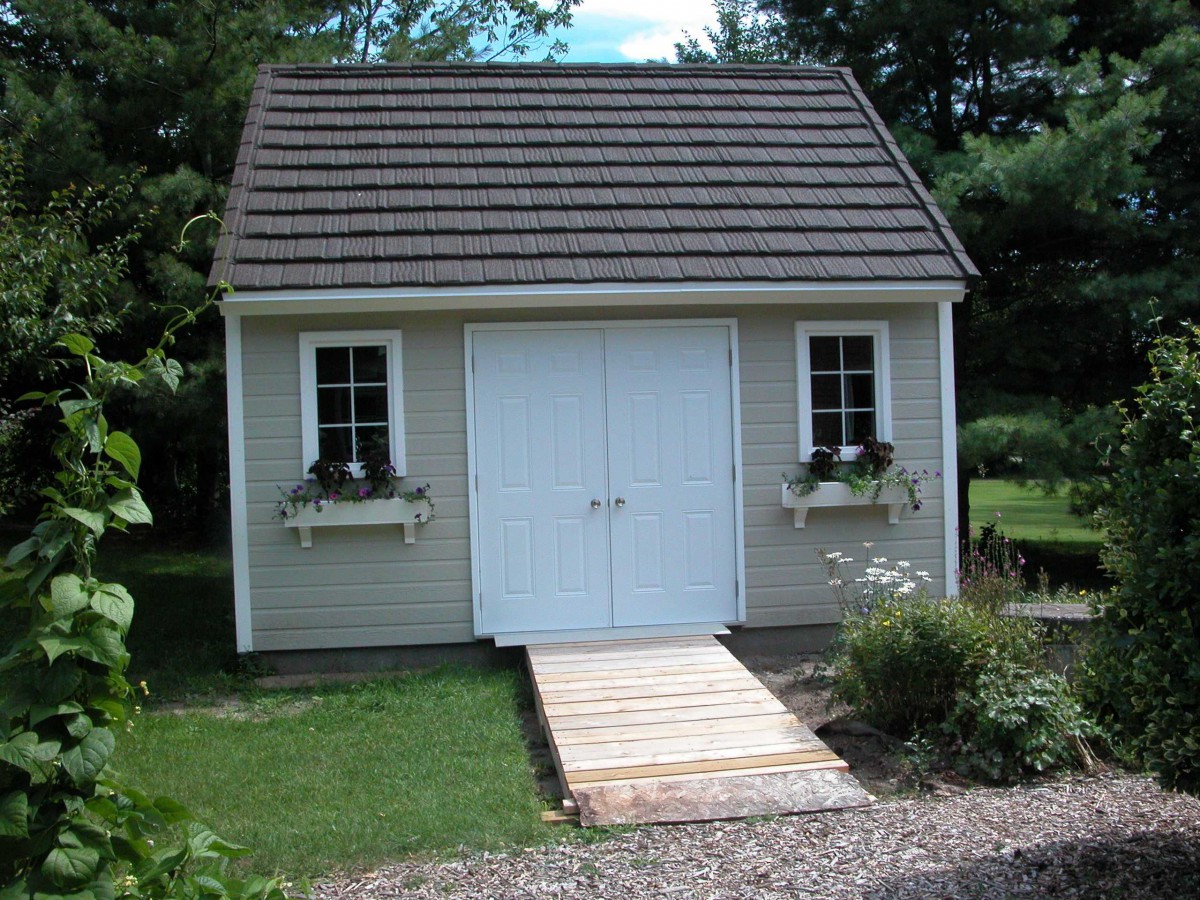 Telluride shed design 14 x 15 with white accessories in a backyard seen from the front. ID number 3278-4.