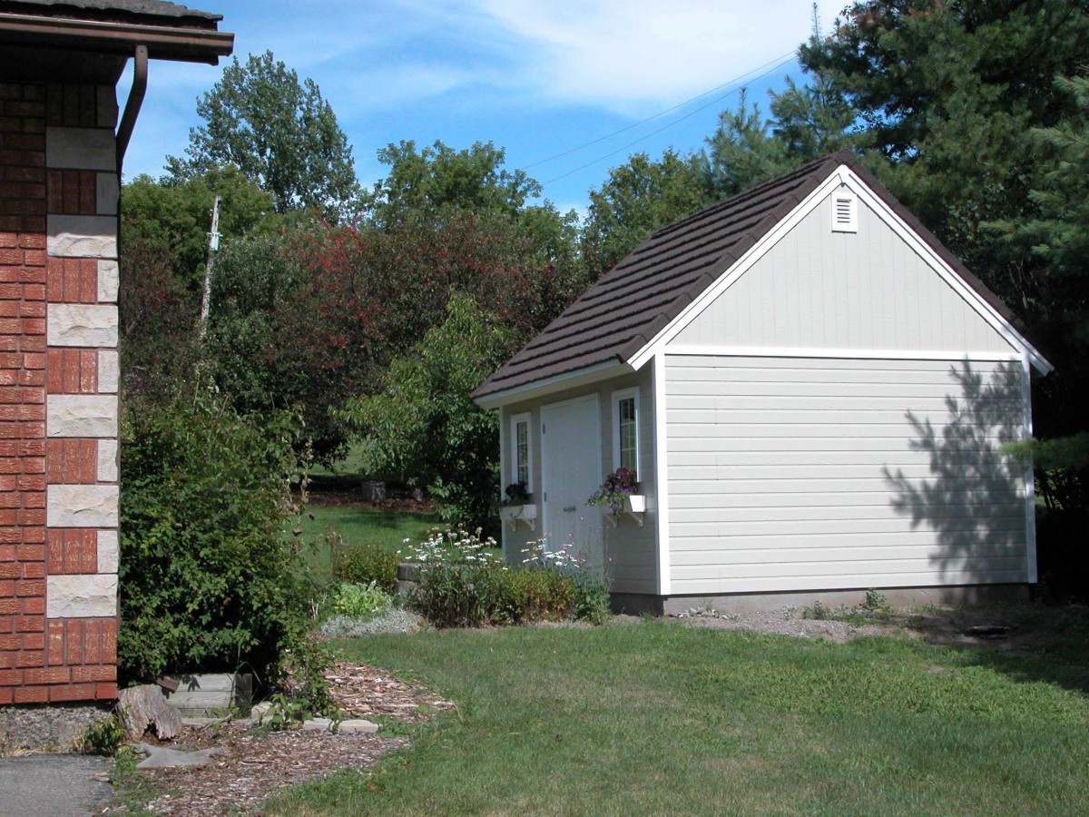 Telluride shed design 14 x 15 with white accessories in a backyard seen from the side. ID number 3278-5.