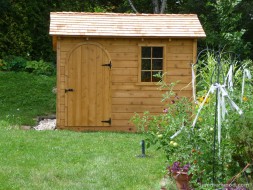 Backyard bar harbor shed plan 8' x 10' with an arched door and a window in a backyard seen from the front. ID number 5664.