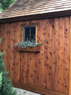 Cedar telluride shed design 10' x 10' in a backyard featuring antique door style as seen from the front. Id number 5746.