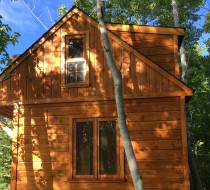 Bala Bunkie cabin plan 10x10 with 20-Lite French Doors and opening Sash windows in a backyard. ID number