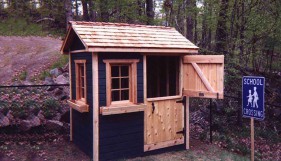 Bear club playhouse design 5  x  7 in backyard with  opening windows seen from front.ID number 2799-3.