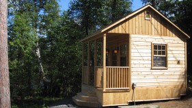 Canmore rustic cabin plan 12 x 14 with a deluxe single door in a backyard seen from the left. ID number 3392-1.