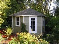 Catalina shed design 11 ft with a white door and windows in a backyard seen from the frontage. ID number 1785-1.