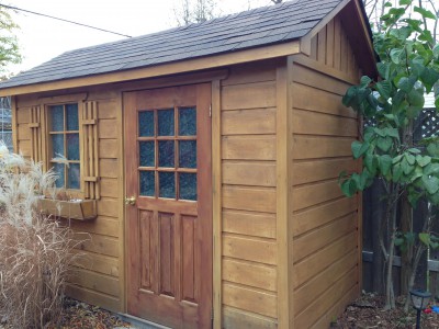 Cedar Palmerston shed design 5' x 10' in a backyard featuring cedar channels and a standard single door as seen from the side. Id number 5760.
